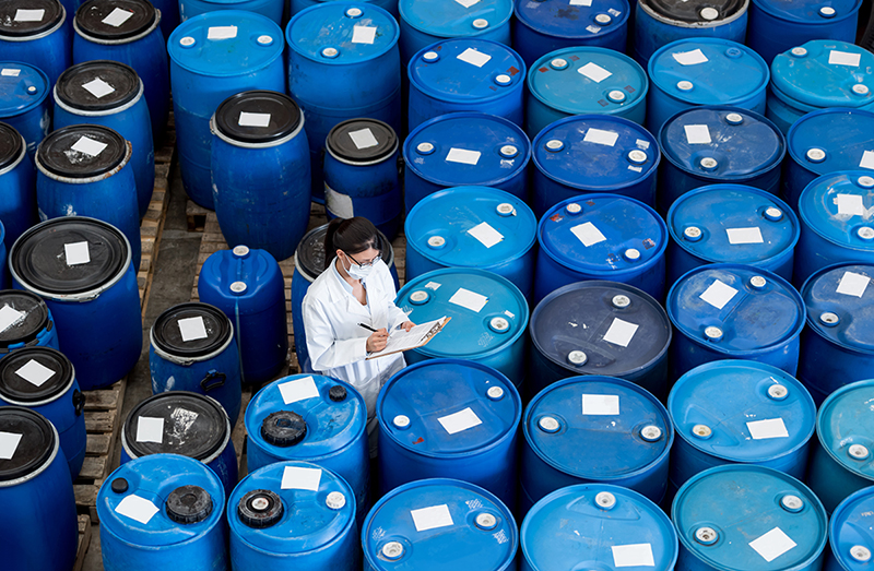 Many Blue Barrels Containing Coating Raw Material Emulsions, a Woman